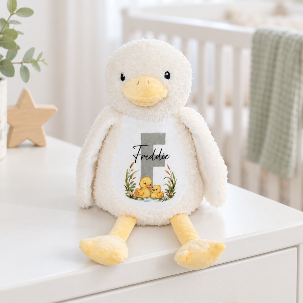 Personalised cream and yellow plush baby duck soft toy with embroidered name Freddie, decorative initial F and duckling illustrations.