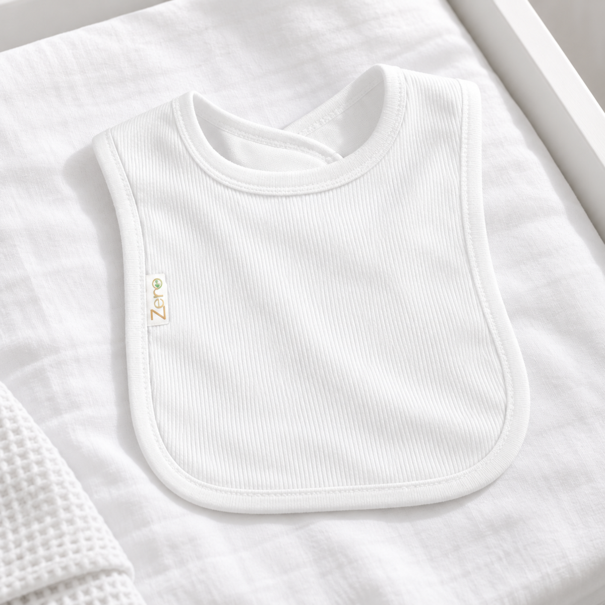 A white ribbed baby bib made of cotton, with short sleeves and a round neckline.