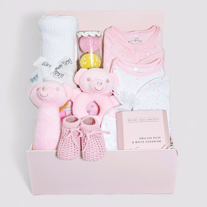 Pink new baby hamper with clothing, blanket, and toys