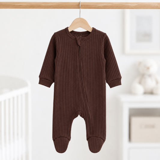 Chocolate brown ribbed cotton baby sleepsuit with long sleeves, enclosed feet and front zip fastening, size 0–3 months, hanging in a neutral nursery