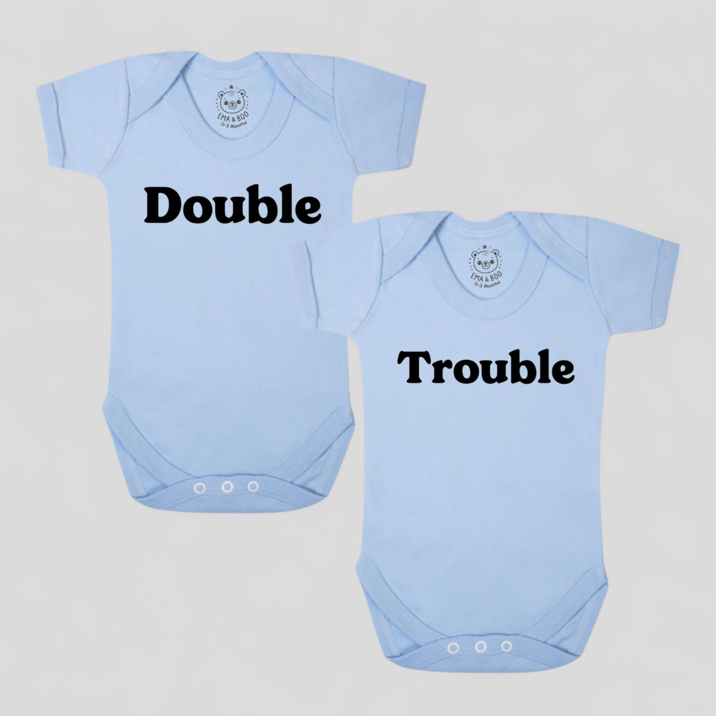 Blue cotton twin bodysuits with “Double” and “Trouble” text – newborn twins gift.