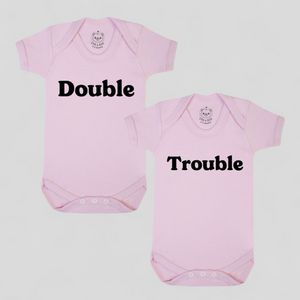 Pink twin baby bodysuits with “Double” and “Trouble” slogans – newborn twin gift set.
