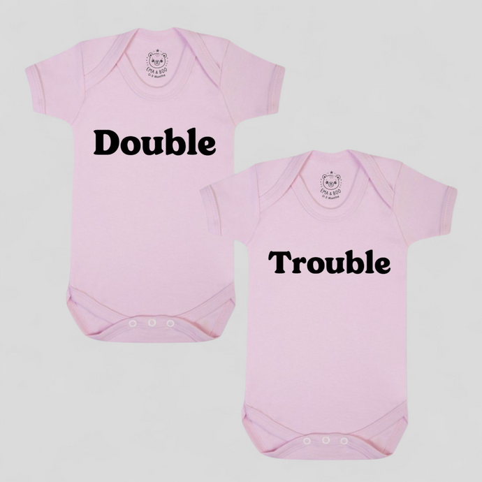 Pink twin baby bodysuits with “Double” and “Trouble” slogans – newborn twin gift set.