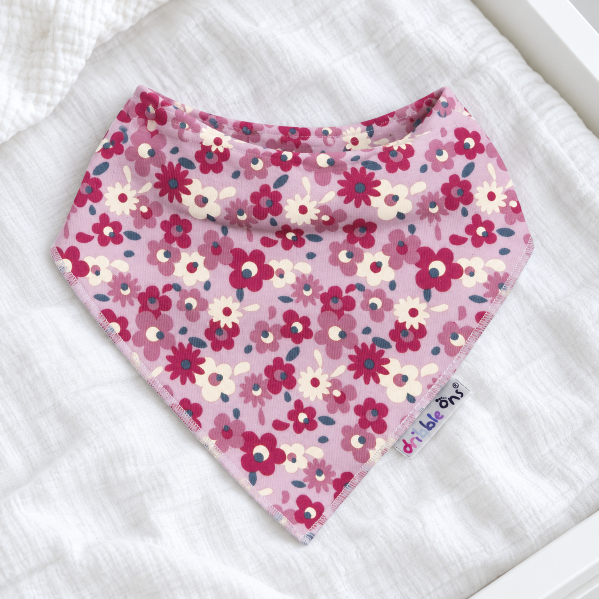 A pink bandana bib with a floral pattern,
