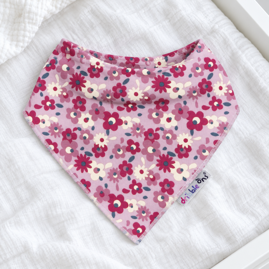 A pink bandana bib with a floral pattern,