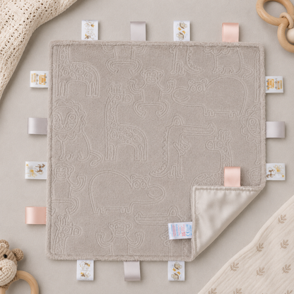 Embossed biscuit baby taggy blanket with sensory ribbon tags measuring 35 x 35cm.