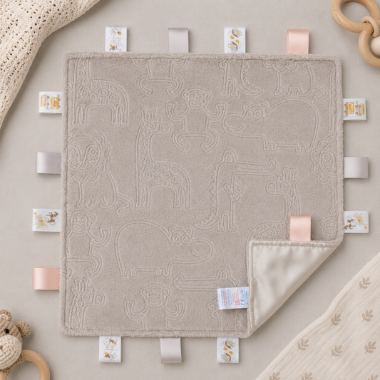 Embossed biscuit baby taggy blanket with sensory ribbon tags measuring 35 x 35cm.