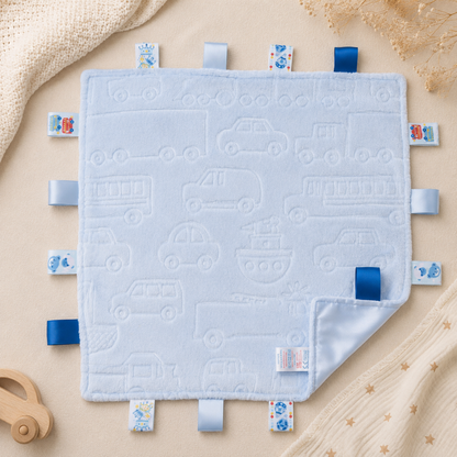 Embossed blue transport baby taggy blanket featuring cars, buses, trains, boats and trucks with sensory ribbon tags measuring 35 x 35cm.