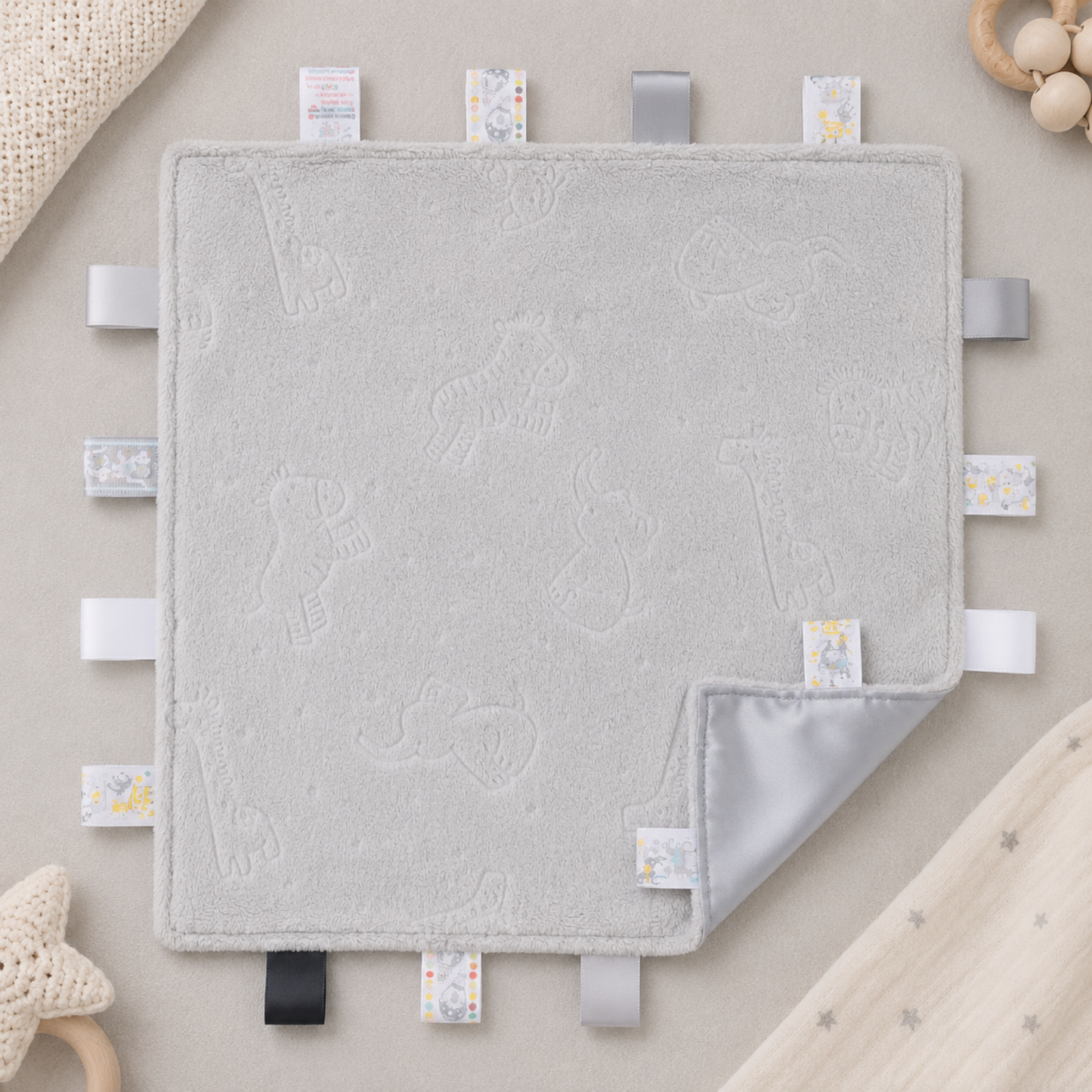 Embossed grey safari baby taggy blanket with sensory ribbon tags and matching grey reverse measuring 35 x 35cm.