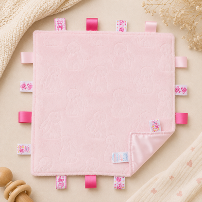 Embossed pink bunny baby taggy blanket with satin sensory ribbon tags and matching pink reverse measuring 35 x 35cm.
