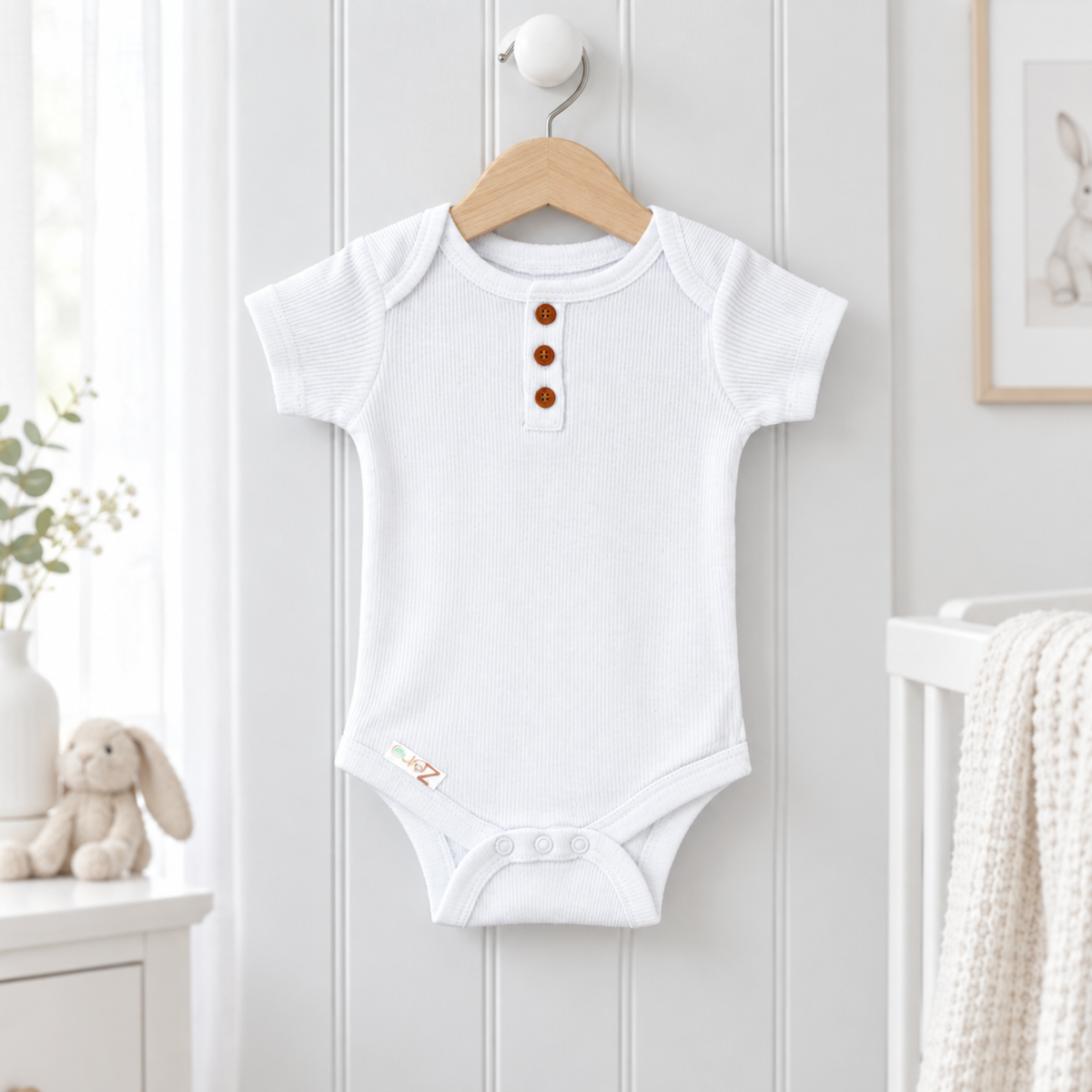 A white short-sleeve baby bodysuit with three brown buttons on the chest.