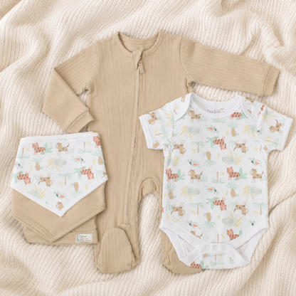 Baby clothing set with beige romper, bibs, hat and patterned onesie on a soft blanket
