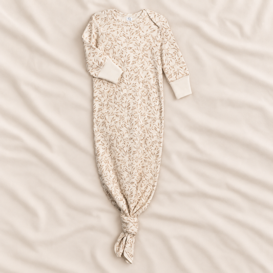 A long-sleeve baby sleep sack with an all-over delicate floral print, laid flat on a soft, cream-colored fabric background.