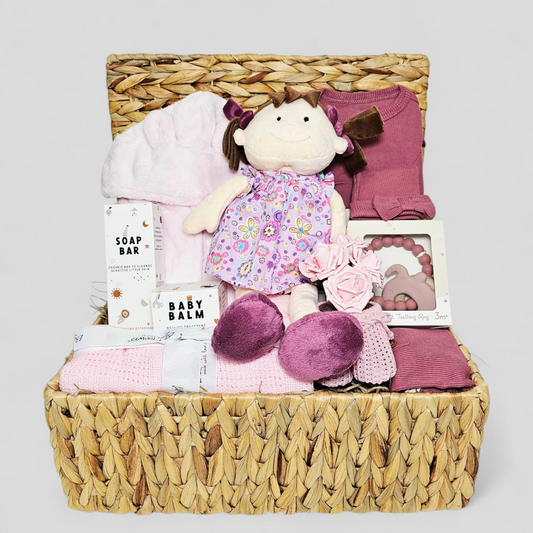 Baby gift basket with plush toy, clothes, and baby products in a woven basket.