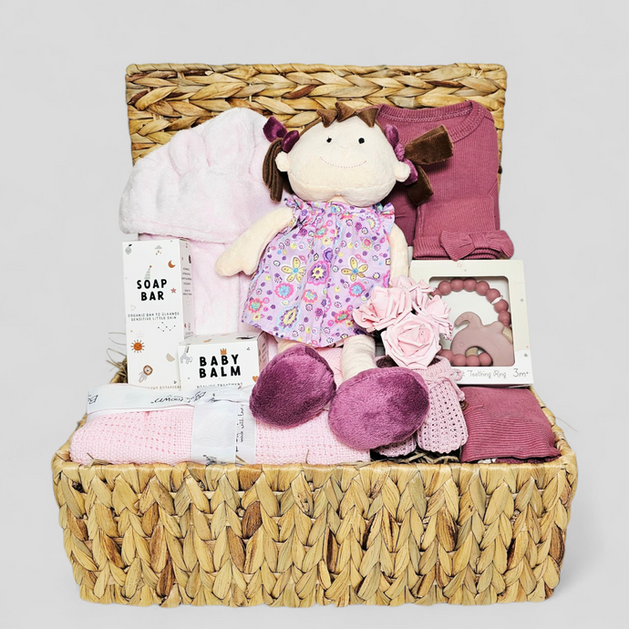 Baby gift basket with plush toy, clothes, and baby products in a woven basket.