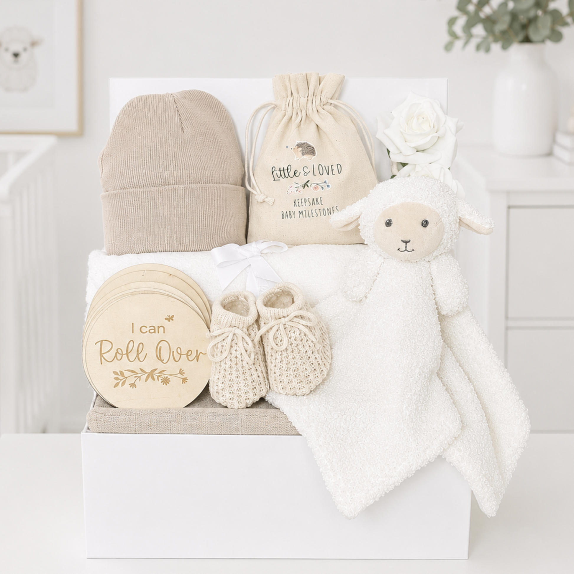 Neutral baby gift box with lamb comforter and milestone discs.