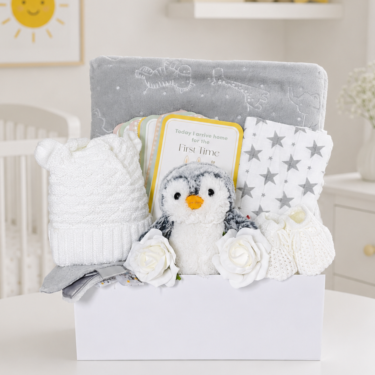 Neutral newborn gift box with penguin plush, milestone cards and grey baby essentials