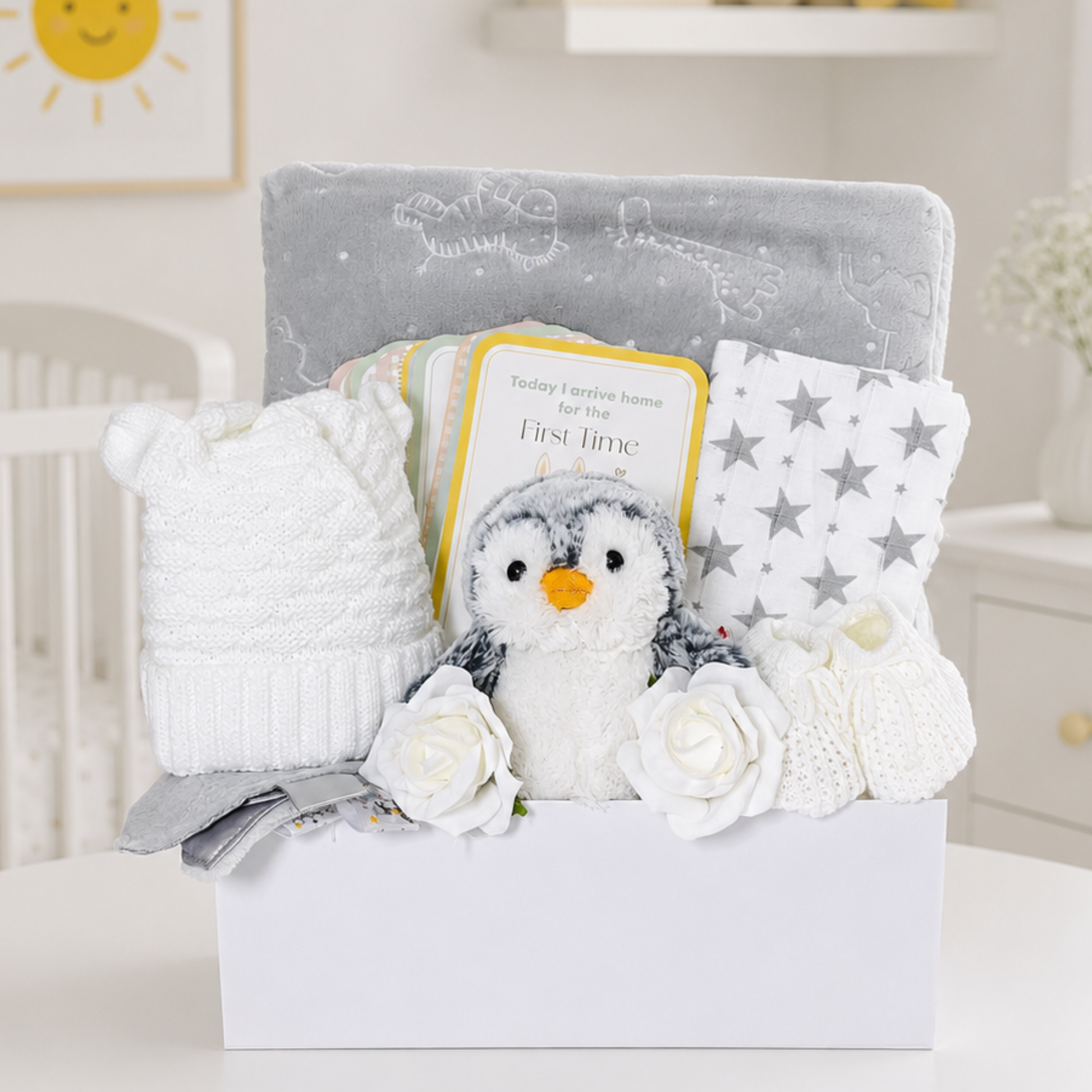 Neutral newborn gift box with penguin plush, milestone cards and grey baby essentials