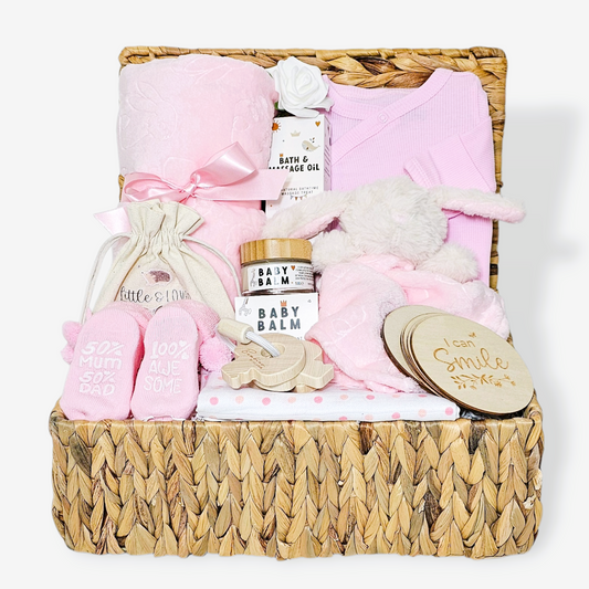 Baby girl gift hamper with pink plush blanket, bunny comforter, sleepsuit, milestone discs and more.