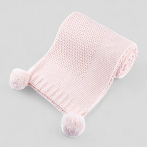 Pink knitted baby blanket with pom-poms 