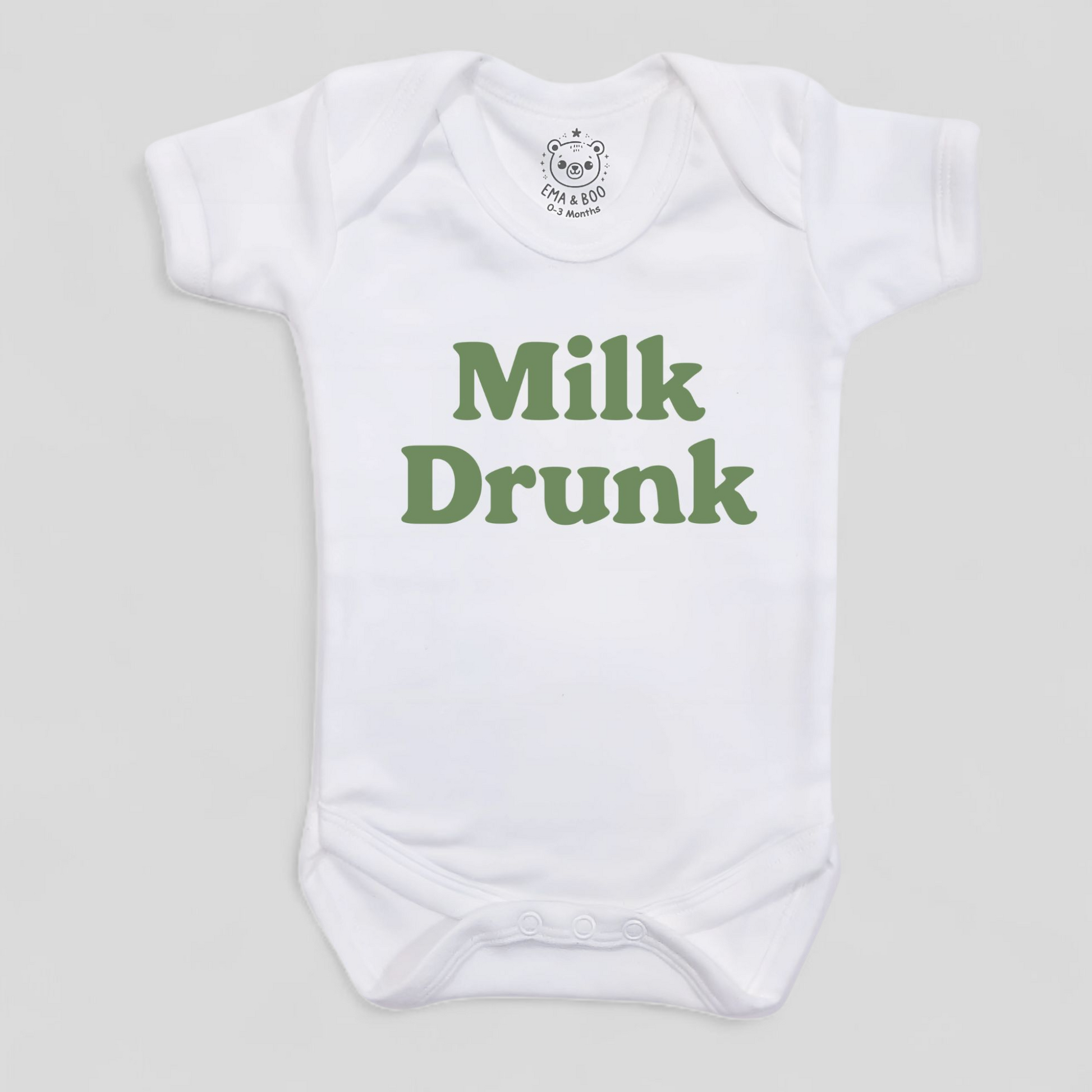White baby onesie with green 'Milk Drunk' text
