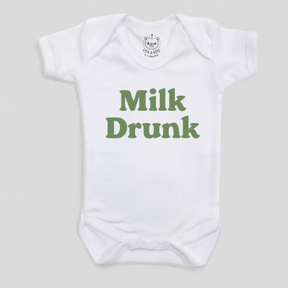 White baby onesie with green 'Milk Drunk' text