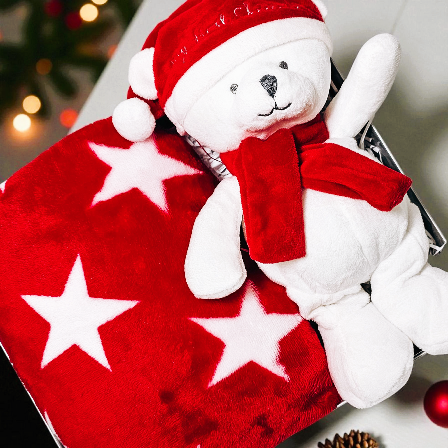 Red star baby blanket with festive white bear in Christmas gift box.