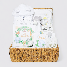 Load image into Gallery viewer, Baby gift basket with items including a plush elephant, baby book, and other baby items in a woven basket.

