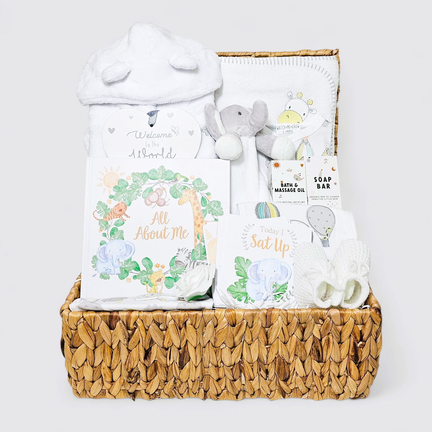 Baby gift basket with items including a plush elephant, baby book, and other baby items in a woven basket.